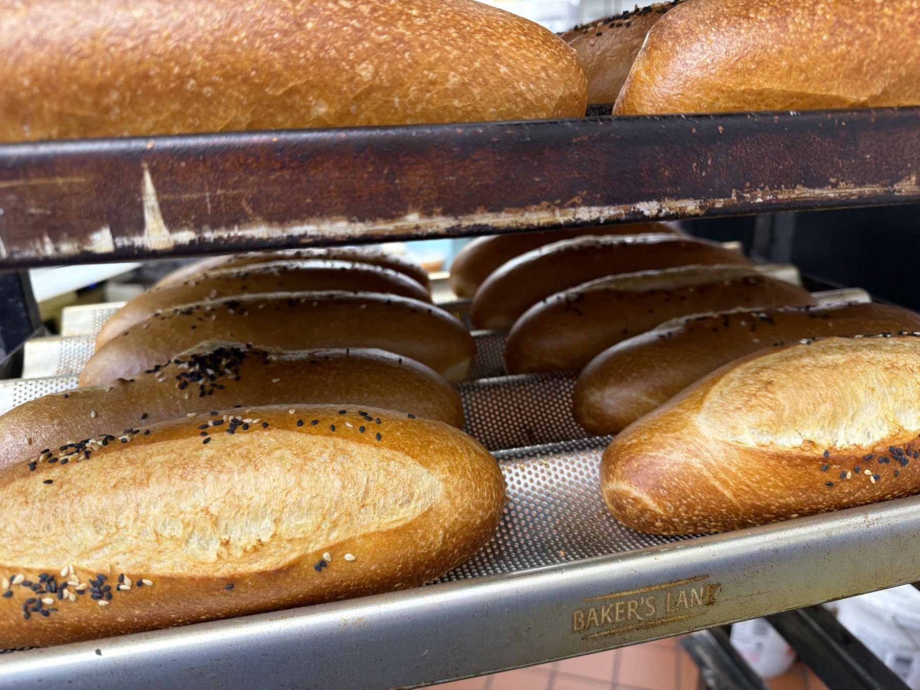 Golden baked baguettes stacked on factory sheet trays