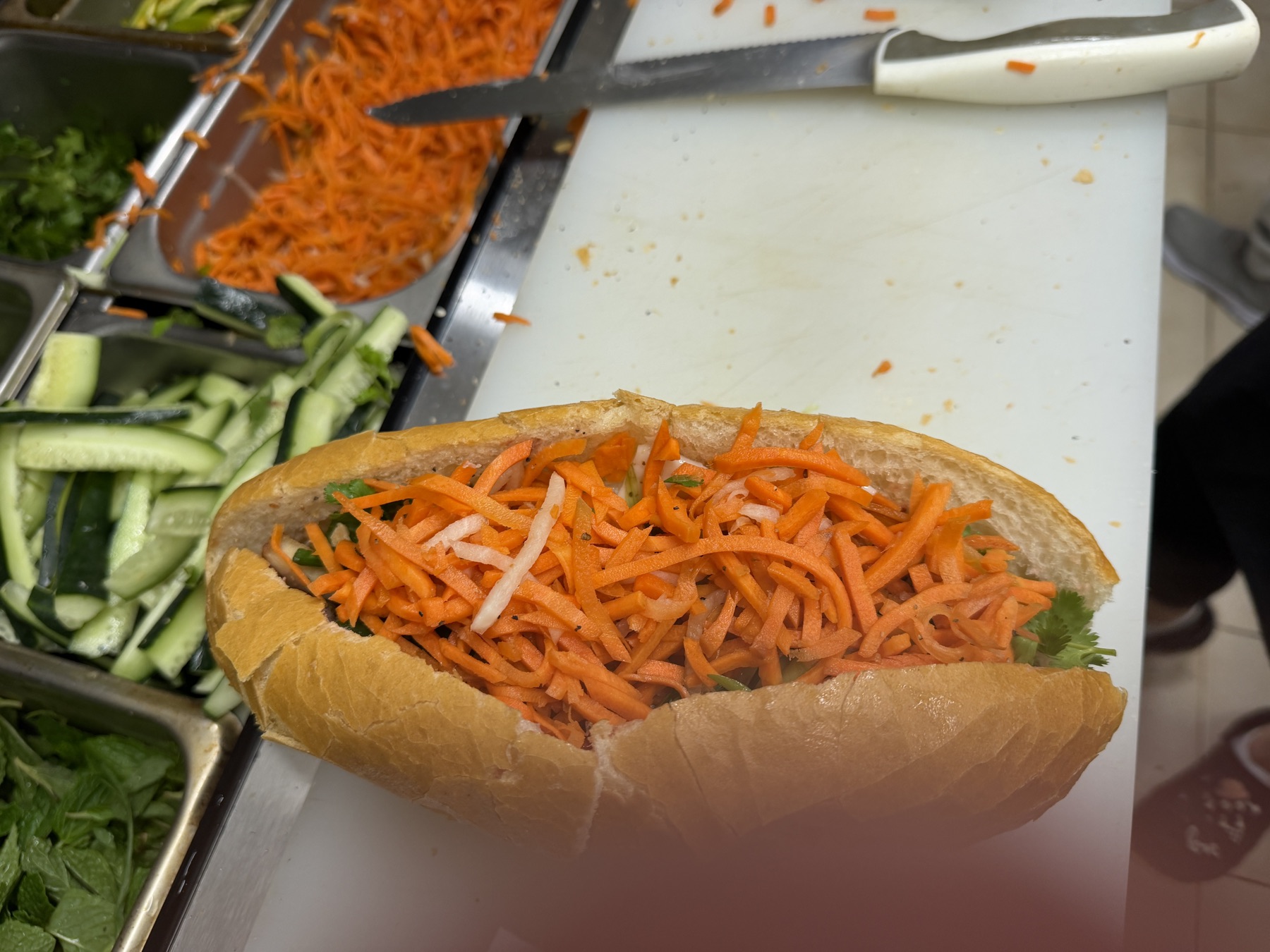 Baguette overflowing with pickled carrots and daikon on the kitchen prep line